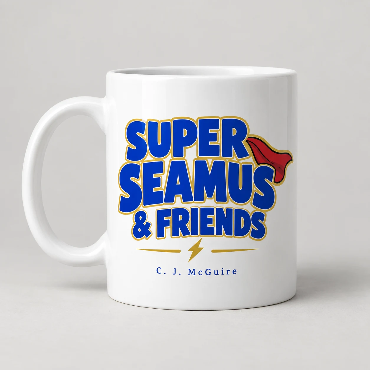 Concept mockup of a white Super Seamus & Friends mug with blue and gold lettering and a red cape motif.