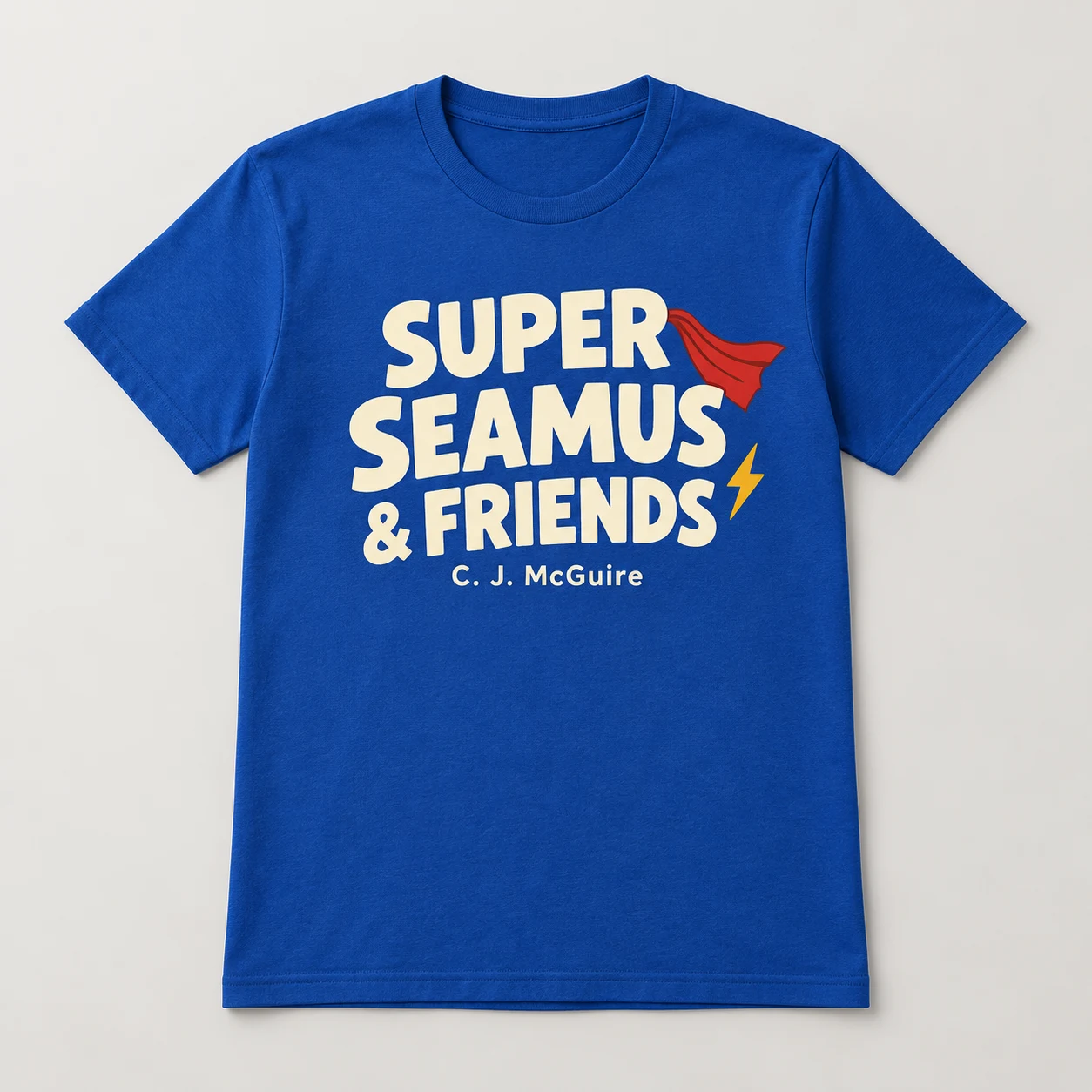 Concept mockup of a royal-blue Super Seamus & Friends series shirt with cream and gold lettering and a red cape motif.